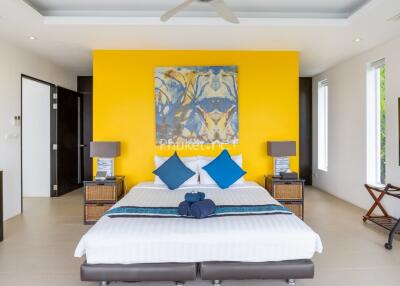 Modern bedroom with a yellow accent wall, double bed, and large painting