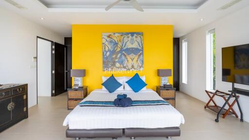 Modern bedroom with a yellow accent wall, double bed, and large painting