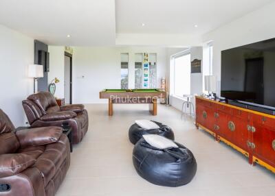 A spacious living room with leather recliners, bean bags, a large flat-screen TV, and a pool table.