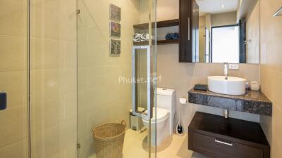 Modern bathroom with glass shower, sink, and toilet