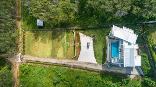 Aerial view of a modern house with a pool and surrounding green landscape