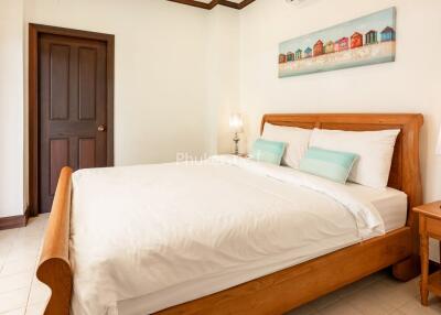 Bedroom with a large wooden bed, bedside tables, lamps, and a wall painting