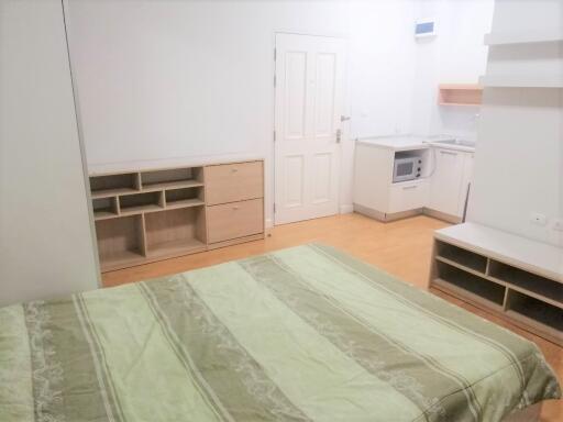 Studio apartment with bed, built-in storage, and kitchen area
