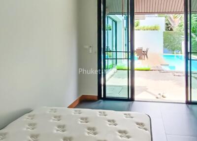 Modern bedroom with large sliding glass doors leading to a pool area