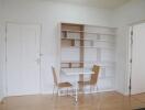 Minimalist dining area with table, chairs, and shelving unit
