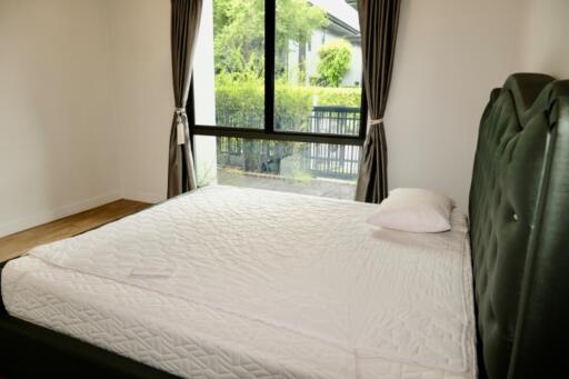 spacious bedroom with large window and green headboard