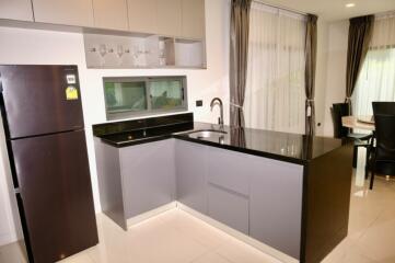 Modern kitchen with black countertops, grey cabinets, and stainless steel appliances