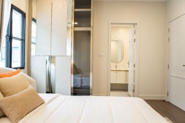 Modern bedroom interior with large windows, white bed, and view of an ensuite bathroom