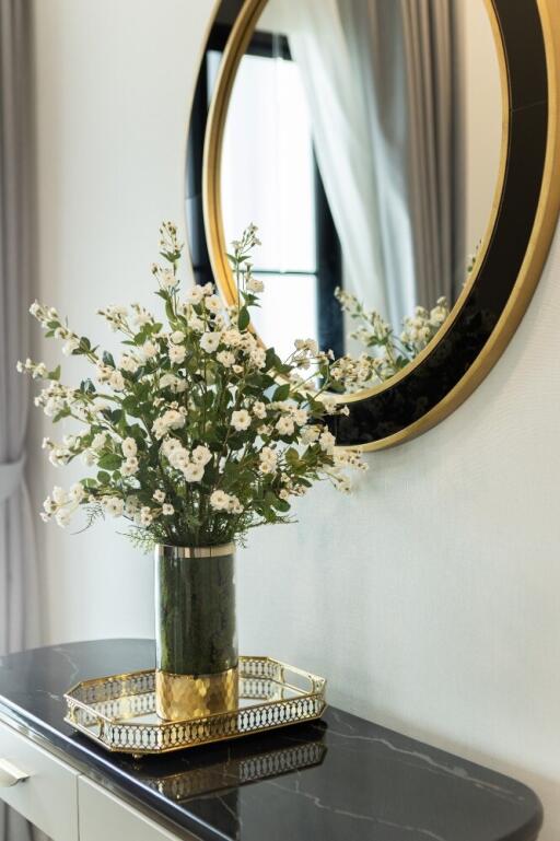 Decorative vase with flowers on a modern dresser, next to a round mirror