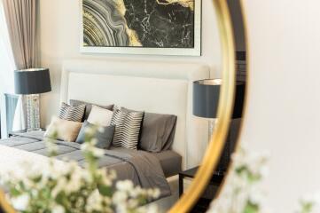 Modern well-decorated bedroom with a mirror, lamps, and a bed with throw pillows