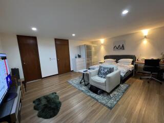 Modern bedroom with wooden flooring, double bed, and seating area