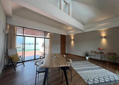 Spacious, modern living area with high ceilings, a large window, and balcony access