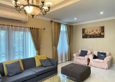 A well-furnished living room with a sofa, chairs, coffee table, chandelier, and wall art