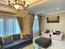 A well-furnished living room with a sofa, chairs, coffee table, chandelier, and wall art