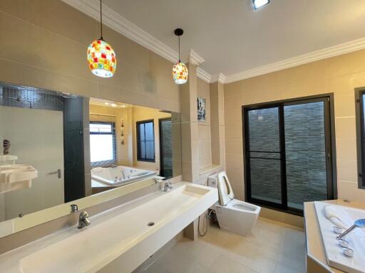 Modern bathroom with double sink, shower, toilet, bathtub, and decorative lighting