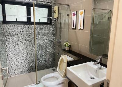 Modern bathroom with glass shower door and mosaic tile wall