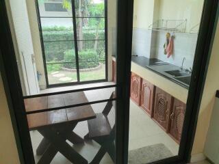 Kitchen area with view to a small outdoor dining space and garden