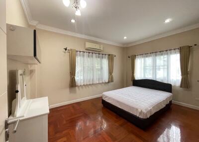 Spacious bedroom with bed, hardwood floor, and multiple windows