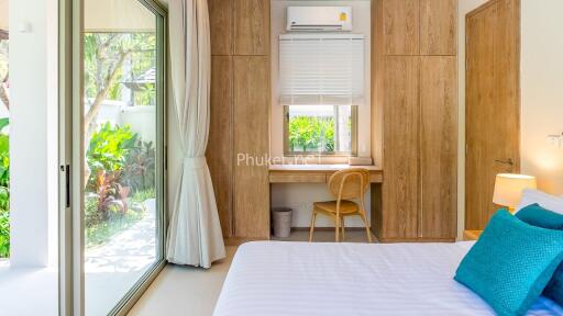 Bright bedroom with a desk and large sliding glass doors opening to a garden