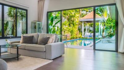 Spacious living room with view of outdoor pool and greenery