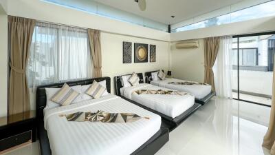 Spacious bedroom with three beds and large windows