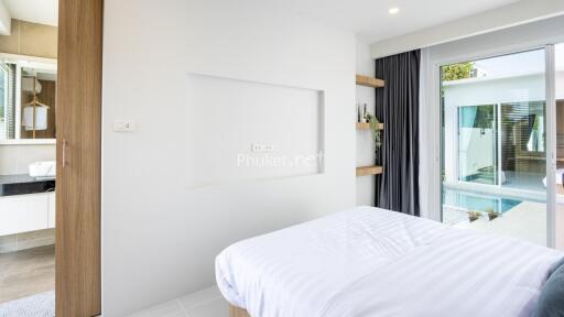 Modern bedroom with a view of a swimming pool and an adjacent bathroom