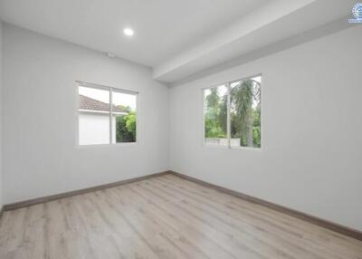 Spacious bedroom with wooden flooring and large windows