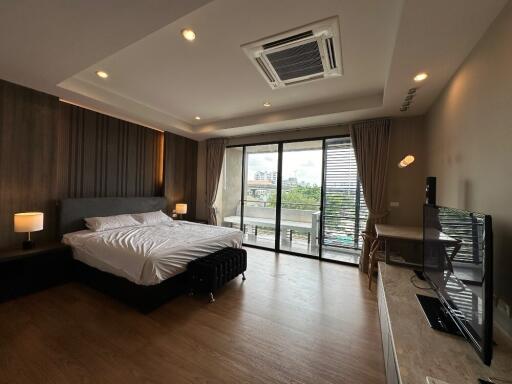 Spacious modern bedroom with large window and wooden floors