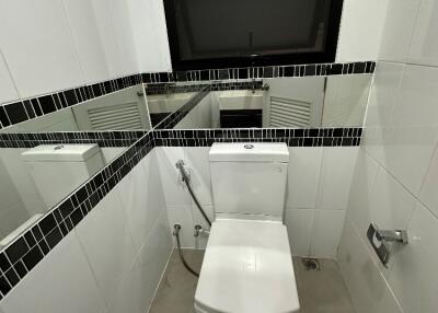Small bathroom with toilet and black-tiled mirror