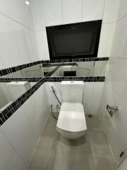 Small bathroom with toilet and black-tiled mirror