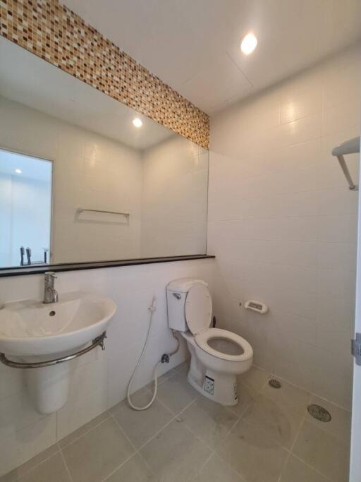 Modern bathroom with large mirror and tiled wall accent