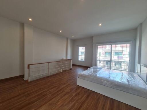 Spacious bedroom with wooden flooring and natural light