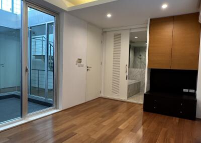 Spacious living room with wooden flooring, recessed lighting, sliding glass doors, and built-in cabinetry.