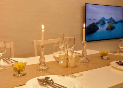 Dining area with a set table, candles, and a wall-mounted TV