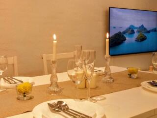 Dining area with a set table, candles, and a wall-mounted TV