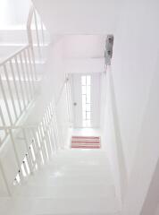 Well-lit white-painted staircase with a white metal railing