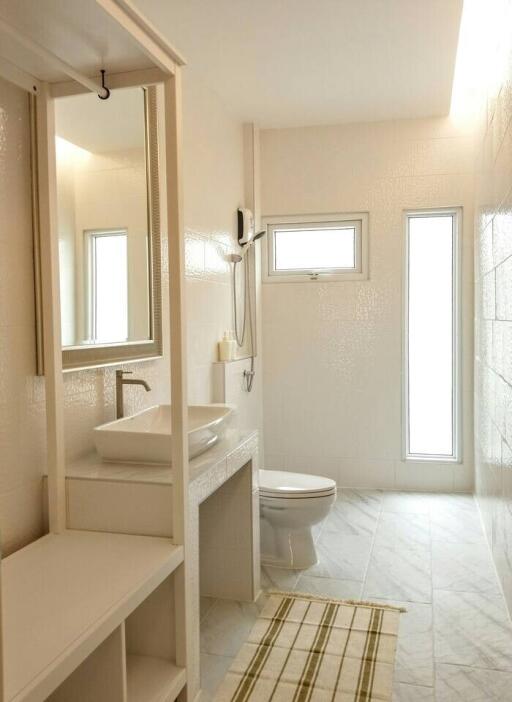 Modern bathroom with vanity, toilet, and window light