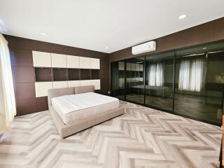Modern bedroom with herringbone flooring, bed, and built-in storage