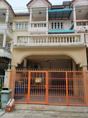 Exterior view of a three-story residential building with a gated front entrance