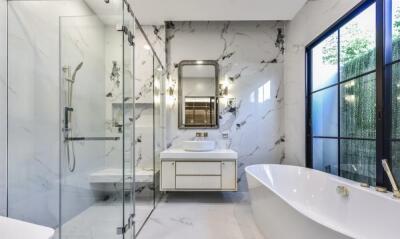 Modern bathroom with glass shower, bathtub, and vanity