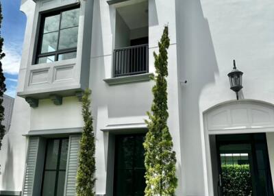 Front facade of a modern white two-story house with large windows and greenery