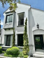 Front facade of a modern white two-story house with large windows and greenery