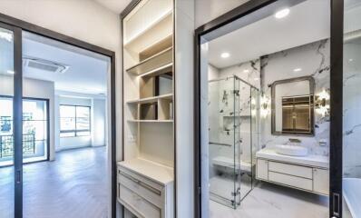 Modern bathroom with glass shower enclosure and nearby hallway