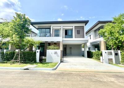 Modern two-story house with a large driveway and well-maintained garden