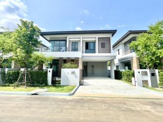 Modern two-story house with a large driveway and well-maintained garden