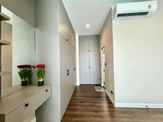 Well-lit hallway with wooden floor, built-in cupboards, and a wall-mounted air conditioner