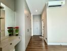 Well-lit hallway with wooden floor, built-in cupboards, and a wall-mounted air conditioner