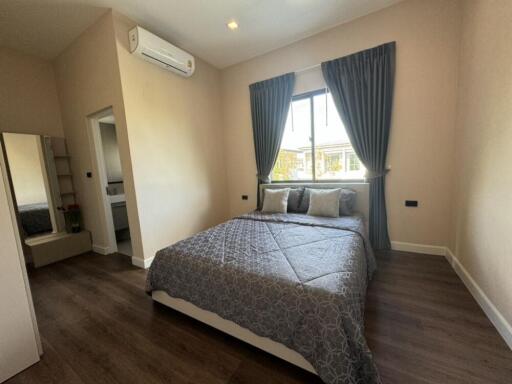 Modern bedroom with a double bed, window, air conditioning and wooden flooring