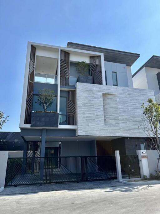 Modern three-story residential building with balconies and greenery