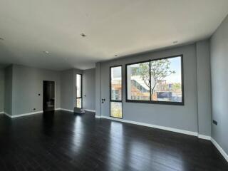 Spacious living room with dark wooden flooring and large windows